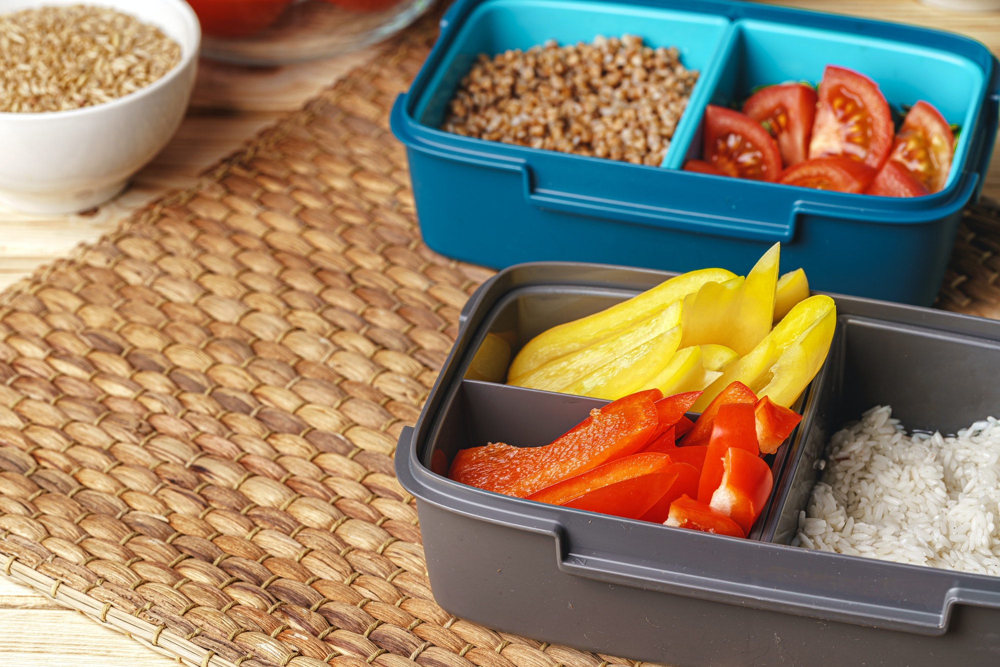 Two lunch boxes with cooked groats and cut vegetables